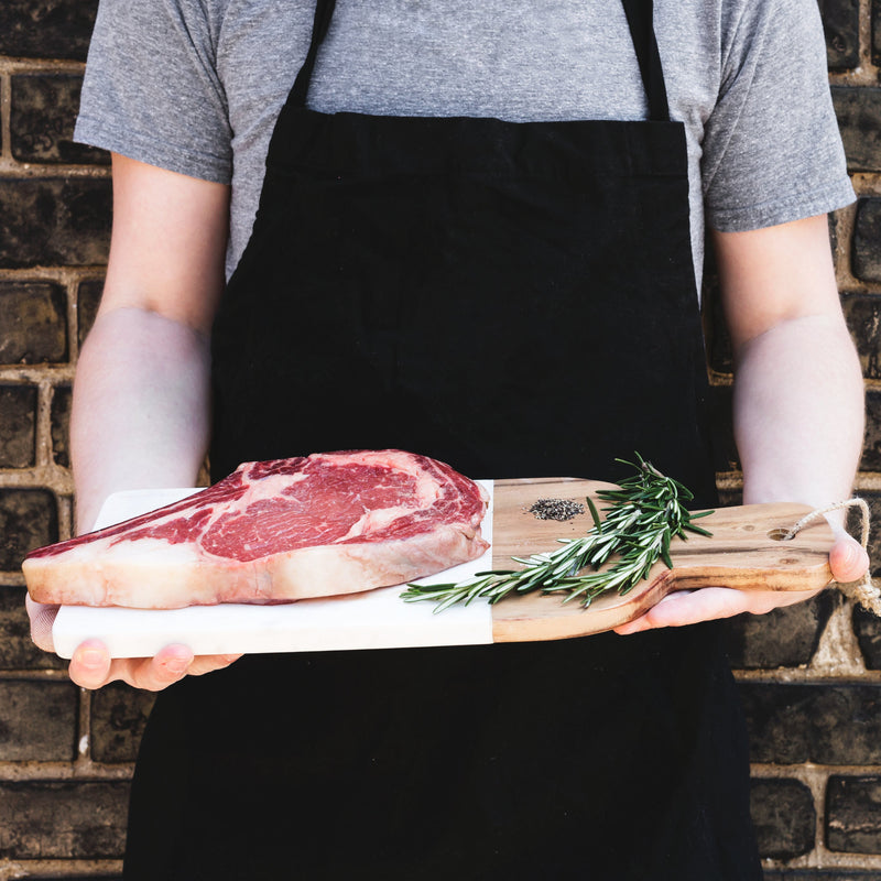 Mann präsentiert Fleisch auf Holzbrett